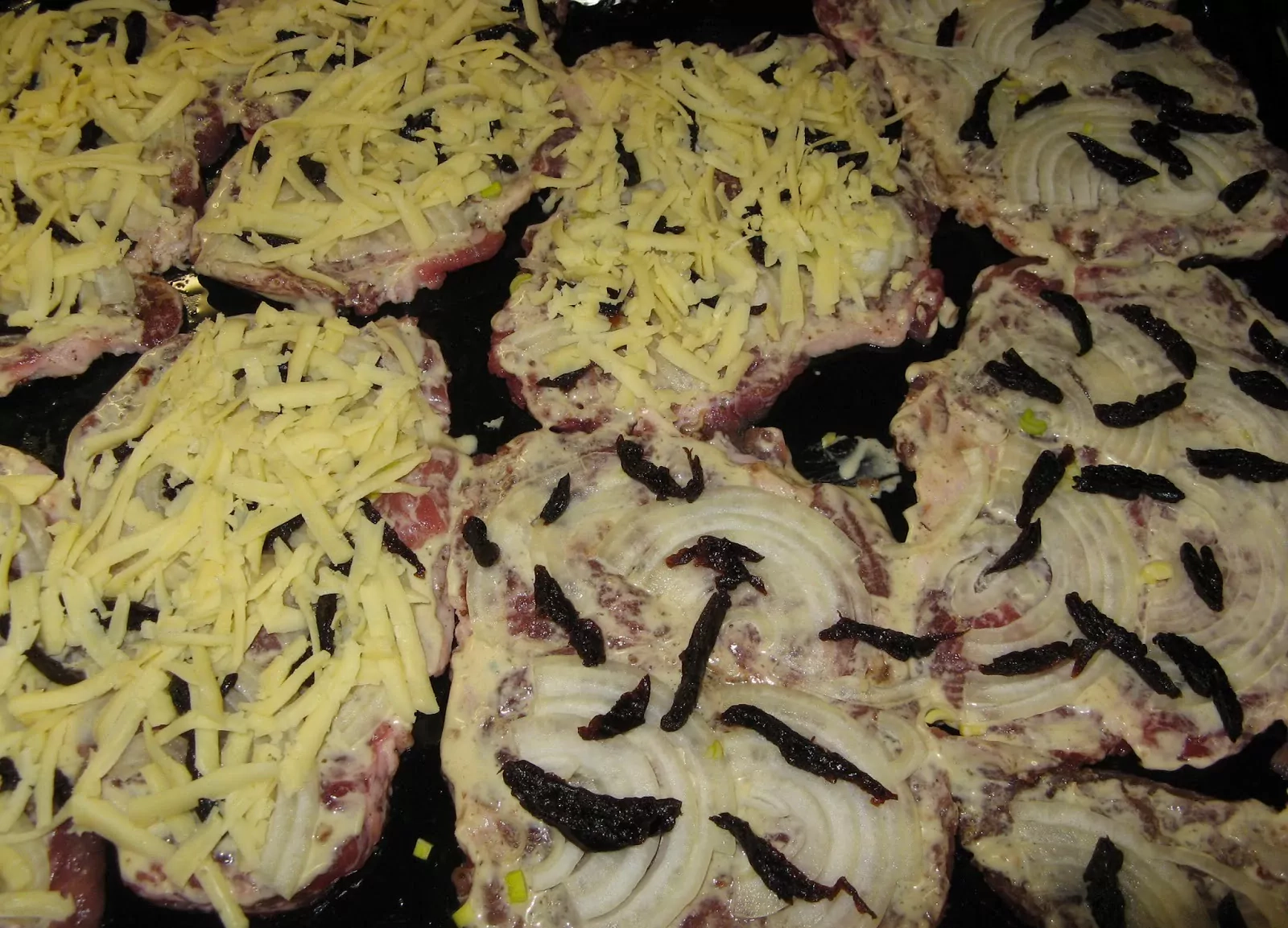 Orkaitėje kepti kiaulienos kepsniai su džiovintomis slyvomis, svogūnais ir sūriu