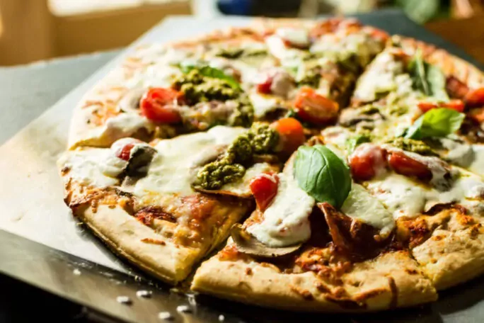 Pizza mit Burata-Käse, geräuchertem Schinken und Pesto-Sauce