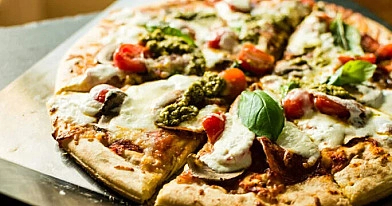 Pizza mit Burata-Käse, geräuchertem Schinken und Pesto-Sauce