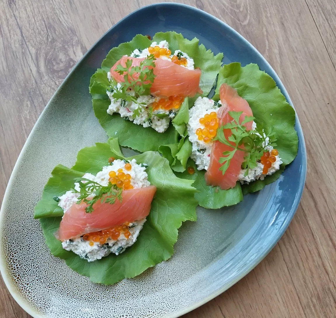 Varškės, krabų lazdelių ir sūdytos lašišos mišrainė salotų pataluose