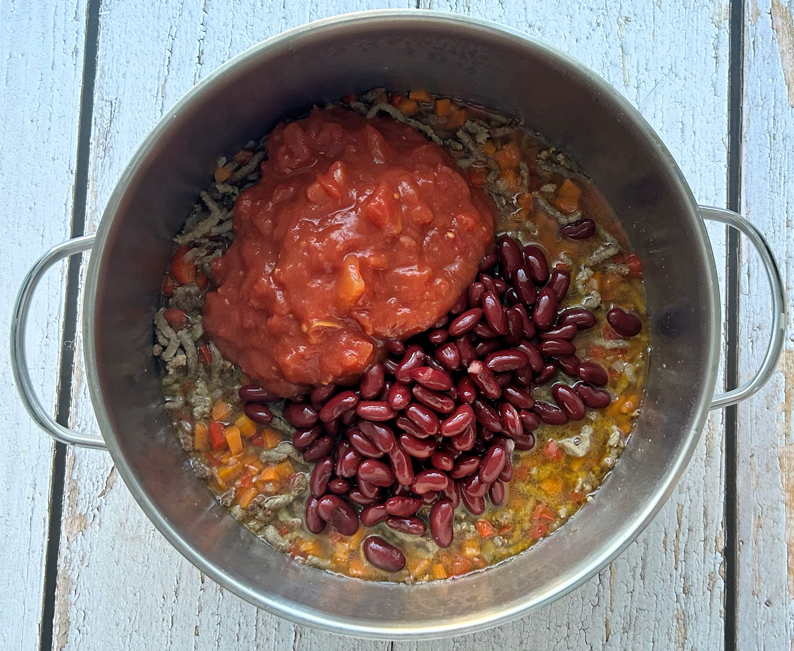 į puodą supilti konservuoti pomidorai