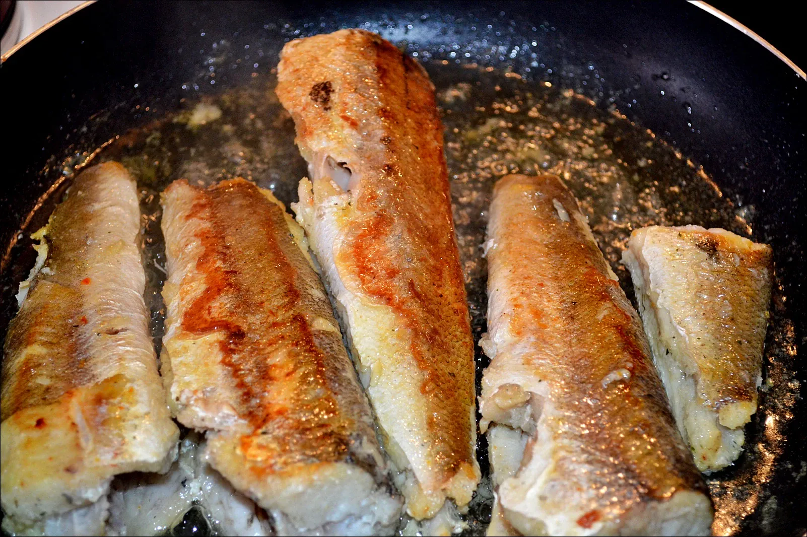 Keptas hekas heptuvėje, patiektas su keptomis bulvėmis ir grietinės-žalumynų užpilu