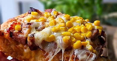 Domowa pizza na grubym cieście z kiełbasą, kukurydzą i serem