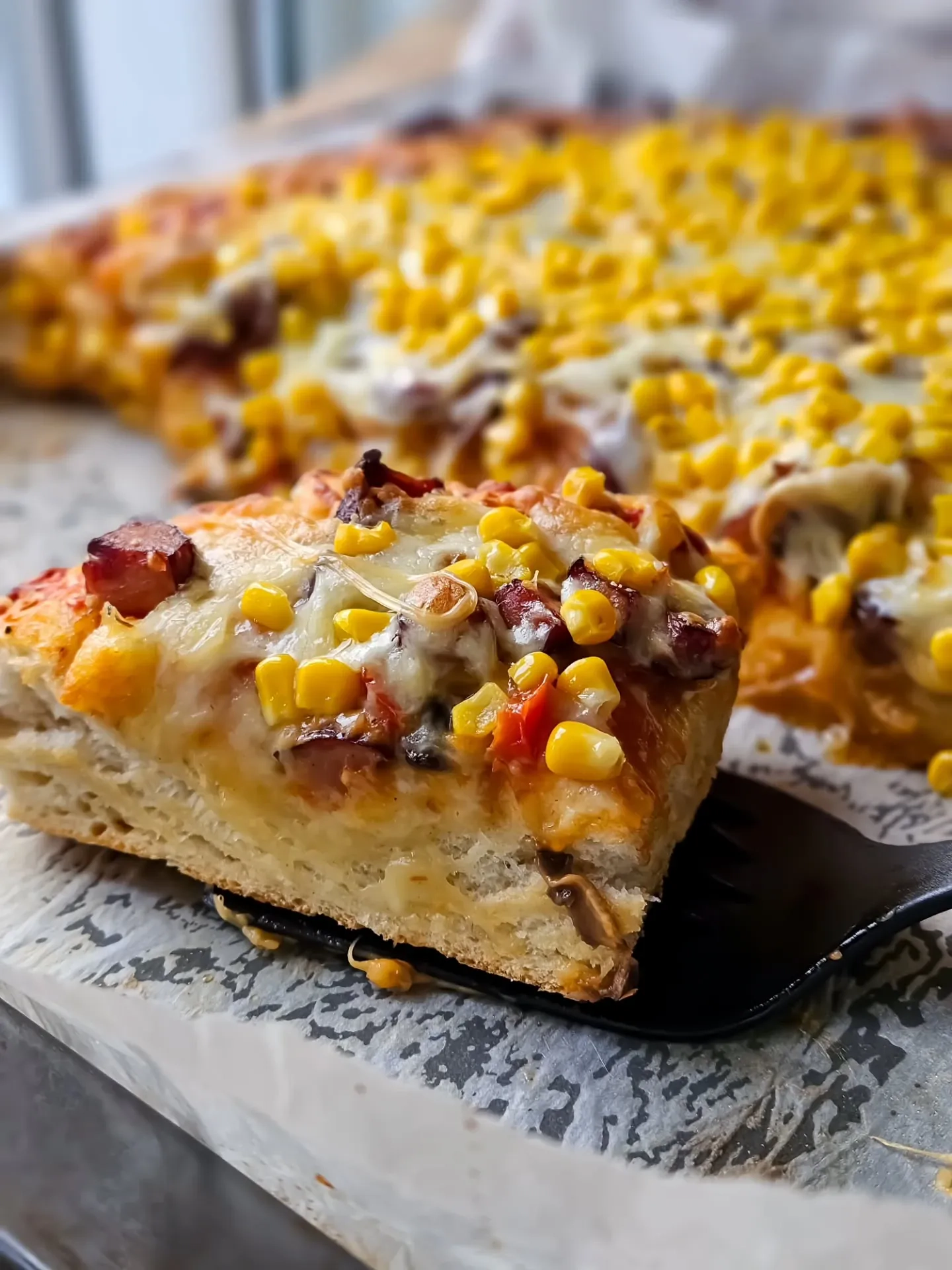 Domowa pizza na grubym cieście z kiełbasą, kukurydzą i serem