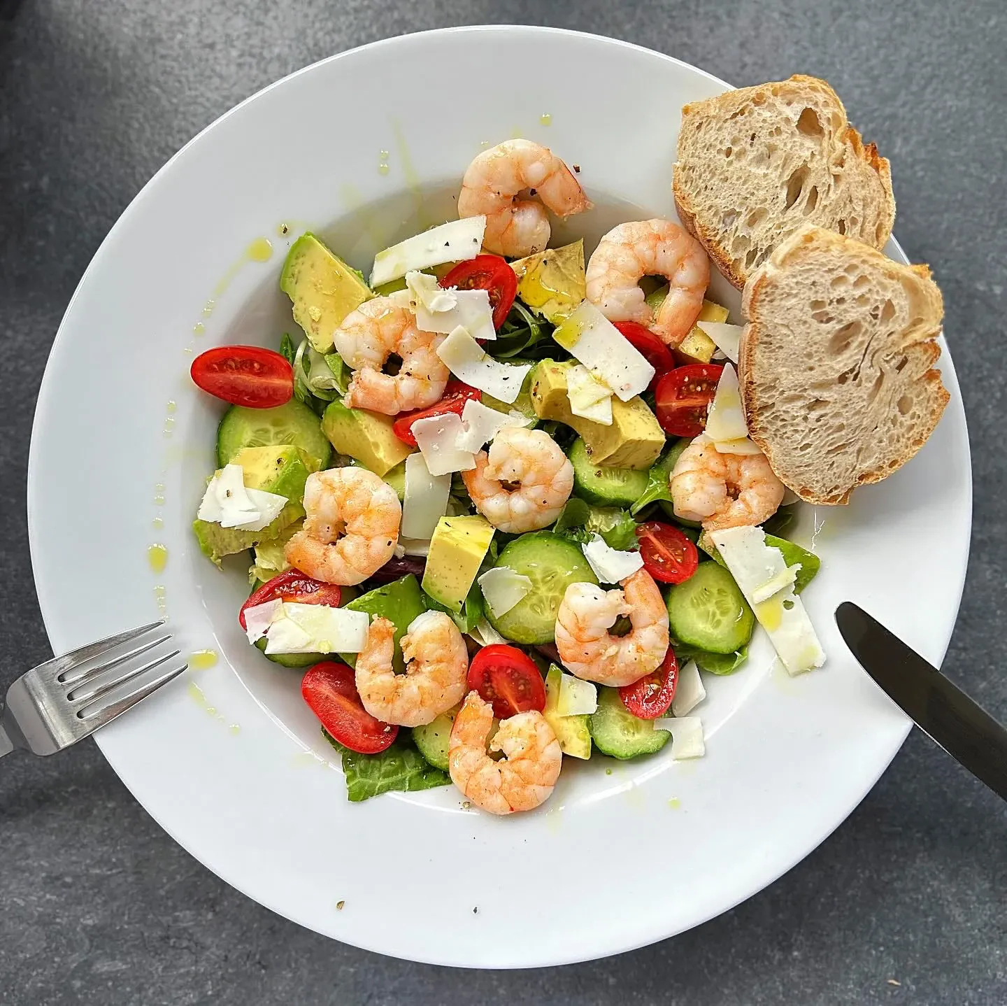 Sałatka z krewetkami, awokado, ogórkiem, pomidorkami koktajlowymi, sałatą i płatkami twardego koziego sera oraz oliwą