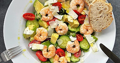 Sałatka z krewetkami, awokado, ogórkiem, pomidorkami koktajlowymi, sałatą i płatkami twardego koziego sera oraz oliwą