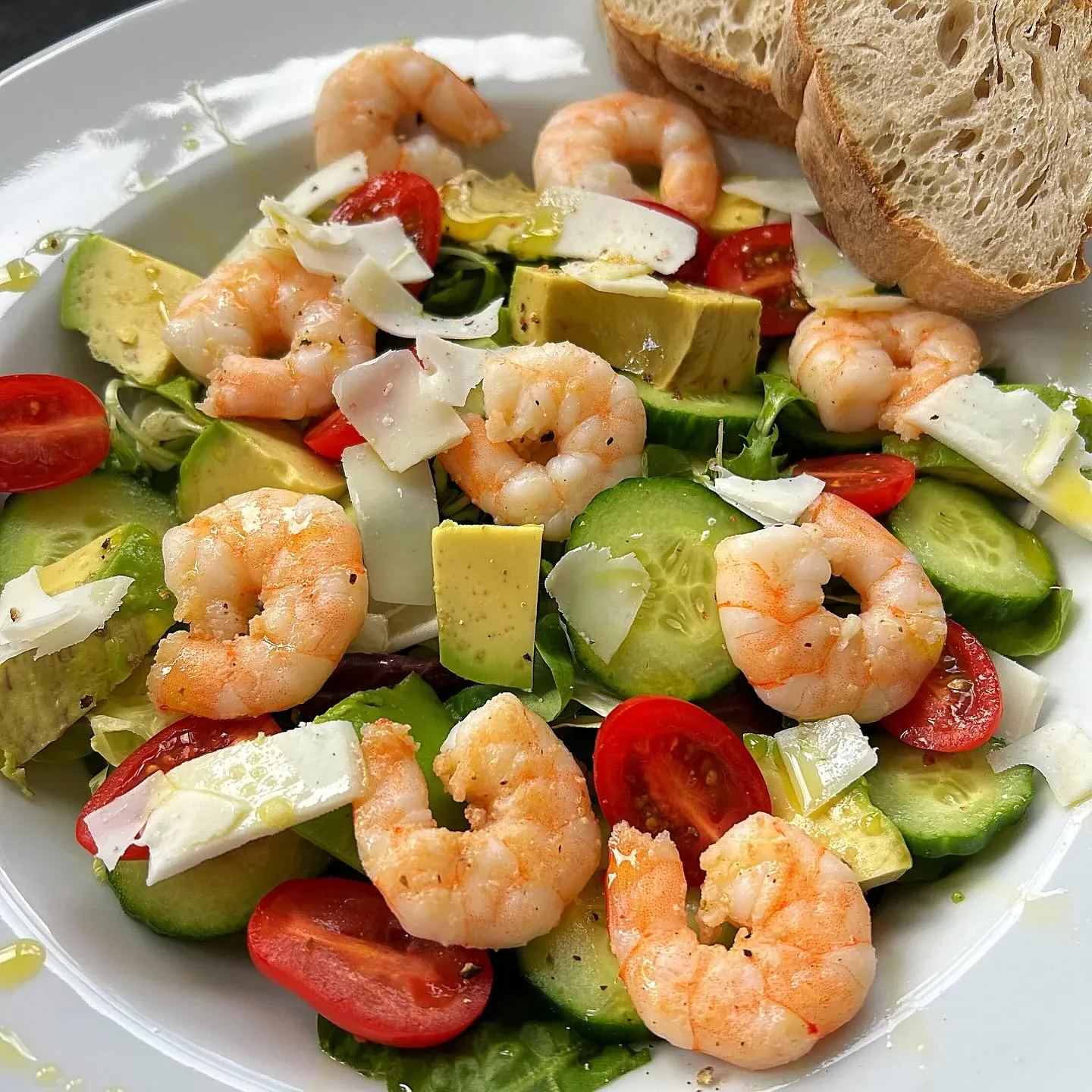 Sałatka z krewetkami, awokado, ogórkiem, pomidorkami koktajlowymi, sałatą i płatkami twardego koziego sera oraz oliwą