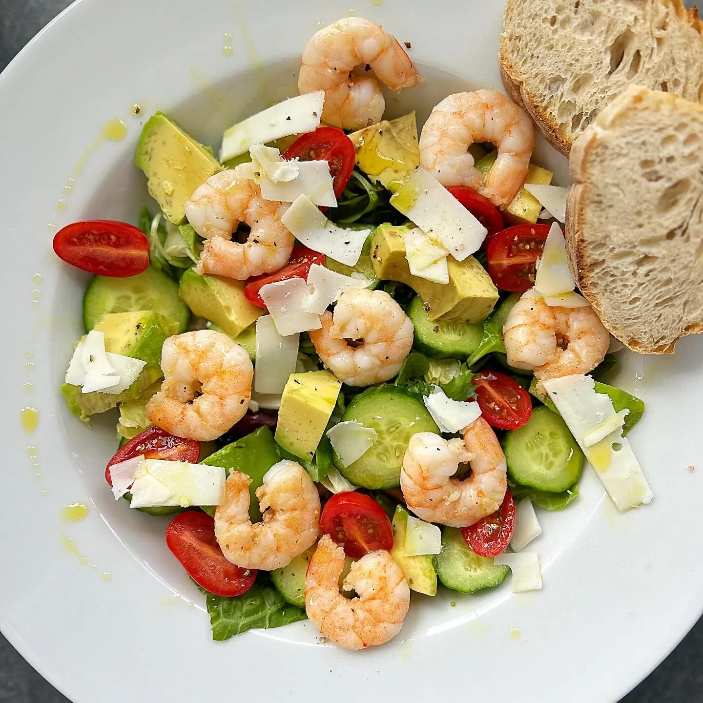 Sałatka z krewetkami, awokado, ogórkiem, pomidorkami koktajlowymi, sałatą i płatkami twardego koziego sera oraz oliwą