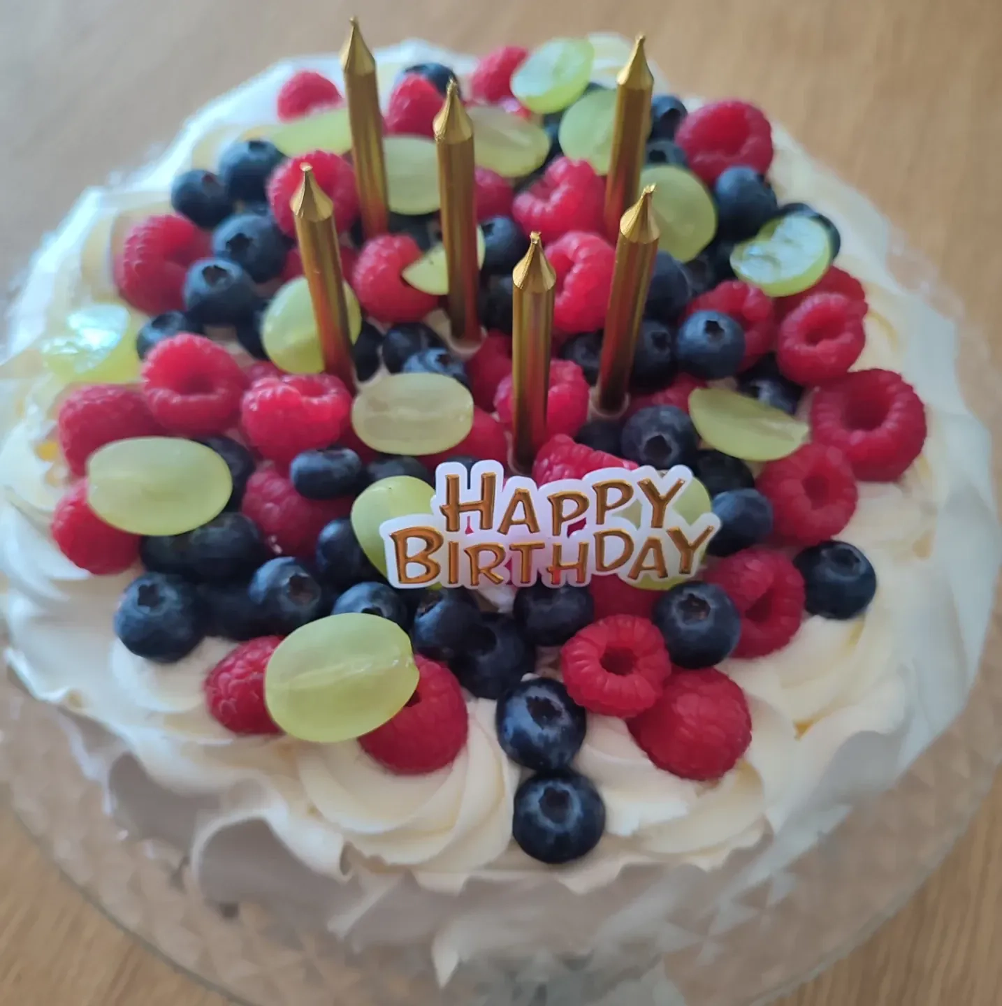 Tort bezowy urodzinowy z bitą śmietaną i owocami leśnymi