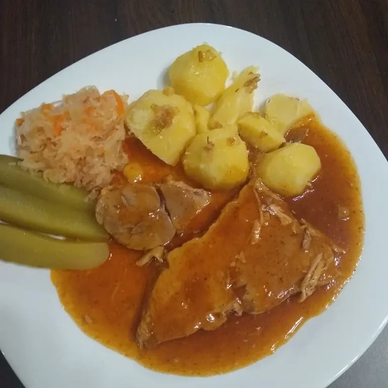 Szynka pieczona w plastrach z ziemniakami, sosem pieczeniowym i dodatkami